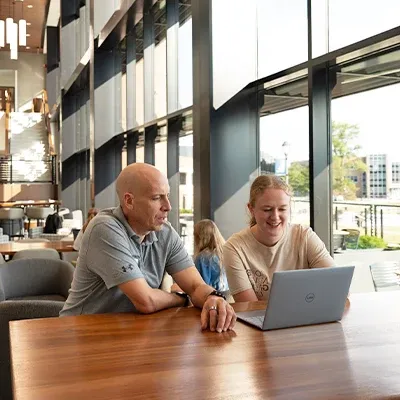 Professor and student looking at laptop and talking.